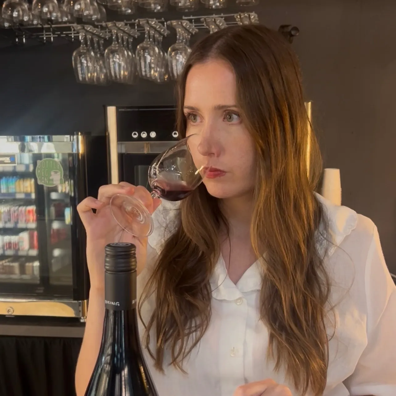 A woman holds a glass of red wine to her lips